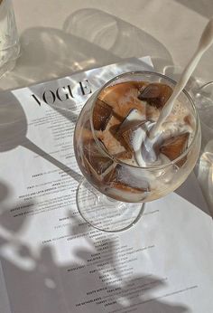 an ice cream sundae sits on a table next to wine glasses and a menu