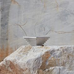 a white sculpture sitting on top of a large rock