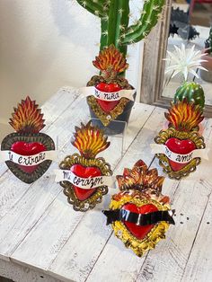 four heart shaped vases on a table next to a cactus