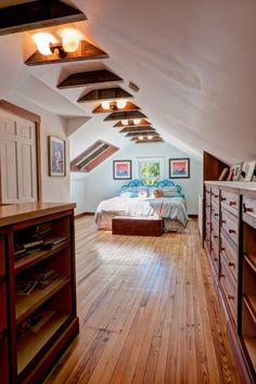 an attic bedroom with hardwood floors and exposed ceiling beams, along with built in bookshelves