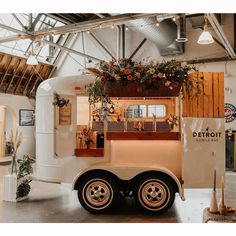 a food truck parked in a building with flowers on the roof and windows above it