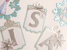 snowflakes and paper cutouts are displayed on a white surface with silver letters