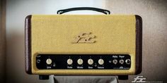 a yellow amp sitting on top of a table next to a brown and white wall