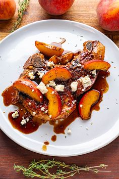 grilled pork chops with peaches and goat cheese on a white plate next to apples