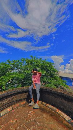 a person on a skateboard in the middle of a brick wall and some trees