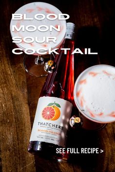 a bottle of blood moon sour cocktail next to an empty glass on a wooden table