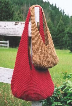 a red purse hanging on a wooden post in front of a field with trees and bushes