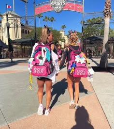 two girls with backpacks walking down the street