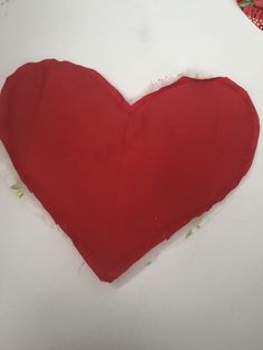 a red heart shaped pillow sitting on top of a table