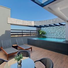 an indoor swimming pool on the roof of a modern building with wooden floors and chairs