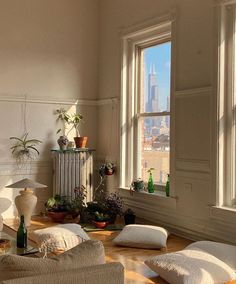 a living room filled with lots of furniture next to two large windows and potted plants