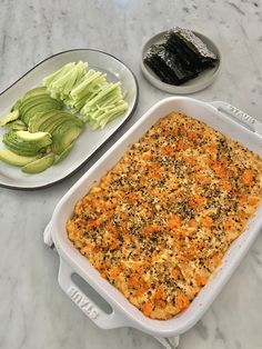 a casserole dish with carrots and cucumbers on the side