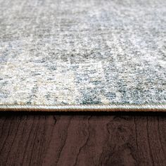 an area rug on top of a wooden floor with a brown and white color scheme