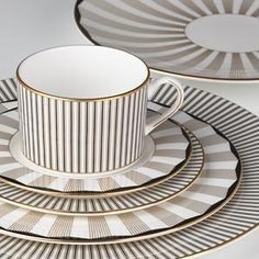 a white and gold striped cup, saucer and plate set on a grey background