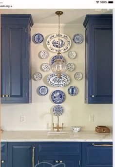 a kitchen with blue cabinets and plates hanging on the wall above the sink, along with an overhead light fixture