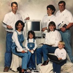 a group of people that are sitting in front of a computer monitor and keyboard, posing for a photo