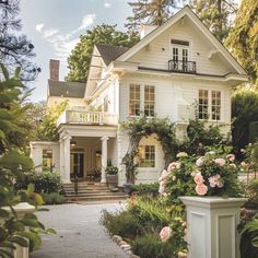 a white house with lots of flowers in the front yard