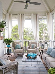 a living room with two couches and chairs on the front porch, covered in white curtains