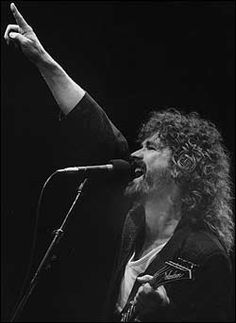 a man singing into a microphone while holding his hand up in the air with both hands