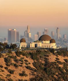 the city skyline as seen from atop a hill in front of a large dome like structure