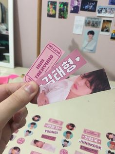 a person holding up a pink sticker with korean characters on it