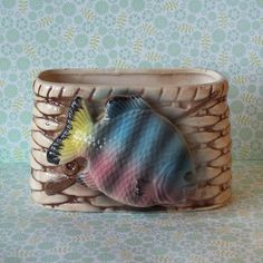 a ceramic fish sitting on top of a basket