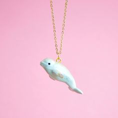 a small white dolphin necklace on a gold chain