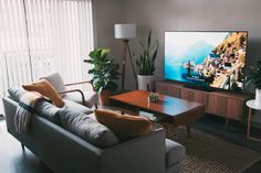 a living room filled with furniture and a flat screen tv on top of a wooden table