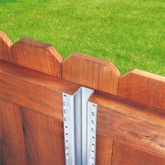 a close up of a wooden door with a metal hinge on the outside and grass in the background