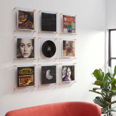 a red couch sitting in front of a wall mounted with pictures and records on it