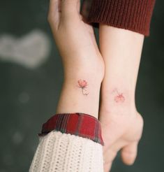 two people with matching tattoos on their arms, both holding each other's hands