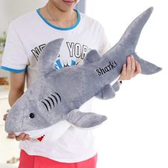 a boy holding a stuffed shark toy in his hands