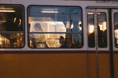 the people are riding on the bus in the city at night and one person is looking out the window