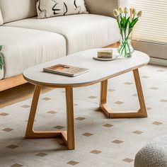 a living room with a couch, coffee table and flowers in vases on the floor