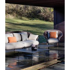 a couch and two chairs sitting on top of a wet ground next to a forest