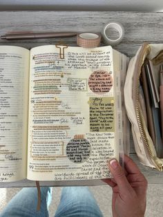 a person holding an open book with writing on it next to other items in a bag