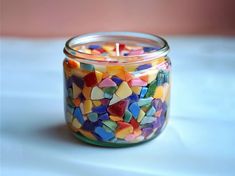 a glass jar filled with colorful confetti sitting on top of a white table