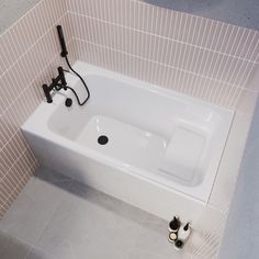 a white bath tub sitting in a bathroom next to a wall mounted hair dryer