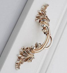 a close up of a door handle on a white door with gold trimmings