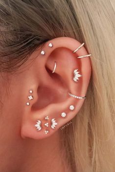 a woman's ear with three different piercings on the middle and one behind her ear