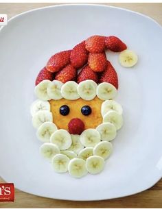 a white plate topped with fruit and a face made out of bananas, strawberries and kiwis