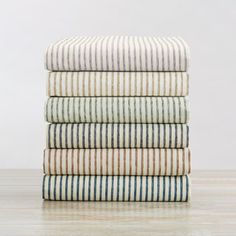 four striped towels stacked on top of each other in various colors and patterns, all folded neatly