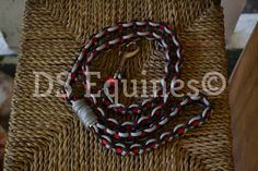 a red, white and black beaded necklace sitting on top of a wicker chair