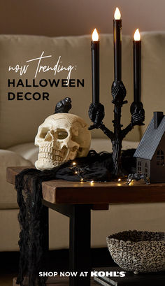 a table with candles and a skull on it in front of a couch that says happy halloween decor shop now at kohl's