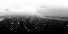 an aerial view of the new york city skyline in black and white with sunbeams