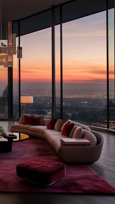 a living room filled with lots of furniture and large windows overlooking the city at sunset