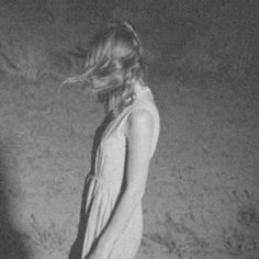 black and white photograph of a woman walking on the beach