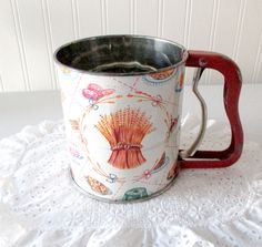 an old fashioned coffee cup on a white doily with a red handle and handles