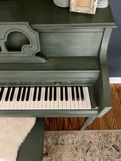 an old piano is painted green and has a white rug on the floor next to it