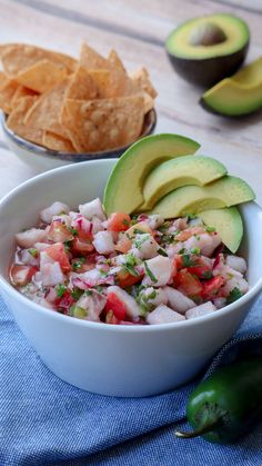 a white bowl filled with guacamole, salsa and tortilla chips